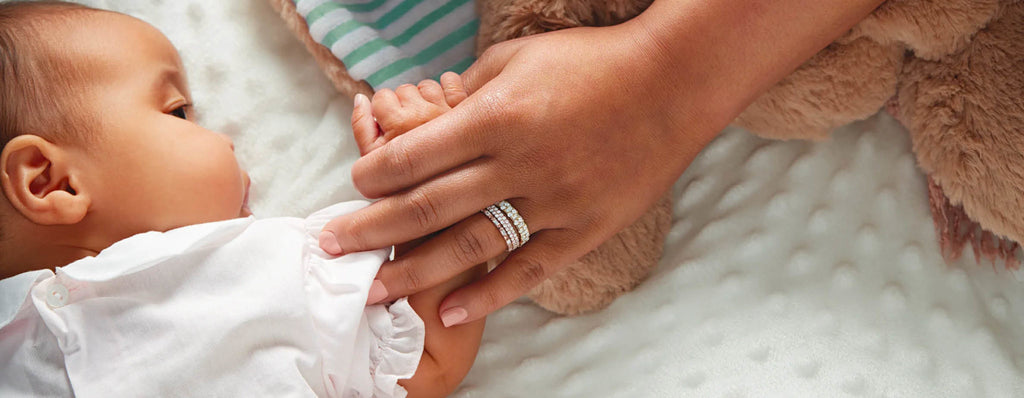 mother wearing anniversary rings and holding her baby's hand, lets build a more sustainable world, together we can make a difference nz moissanite